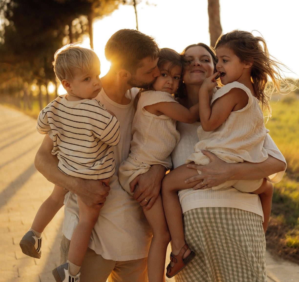 Una familia abrazada al atardecer: los padres con sus tres hijos en brazos.
